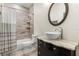 Modern bathroom with granite countertop, a round mirror, and tile shower with shelves at 2600 Robie Ave, Mount Dora, FL 32757