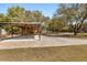 Open-air carport with sturdy wooden supports, spacious concrete area, and a long driveway surrounded by mature trees at 2600 Robie Ave, Mount Dora, FL 32757