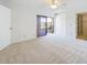 Bright and airy bedroom with a sliding glass door to a balcony, white walls, and carpeted floors at 1009 Royal Oak Blvd, Leesburg, FL 34748