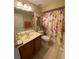 Well-lit bathroom featuring a floral shower curtain and tiled floors at 10846 Point Nellie Dr, Clermont, FL 34711