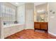 Bathroom with a soaking tub, wood-look floors and wood vanity at 10846 Point Nellie Dr, Clermont, FL 34711