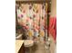 Bathroom featuring a floral shower curtain, toilet, towels and neutral tile flooring at 10846 Point Nellie Dr, Clermont, FL 34711