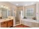 Bright bathroom featuring a soaking tub, tiled walk-in shower, wood cabinets, and a large window at 10846 Point Nellie Dr, Clermont, FL 34711