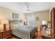 Cozy bedroom featuring wooden floors, ceiling fan, and a large dresser with mirror at 10846 Point Nellie Dr, Clermont, FL 34711