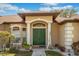 Charming home exterior with a well-manicured lawn, elegant columns, and a stylish green front door at 10846 Point Nellie Dr, Clermont, FL 34711