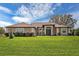 Charming single-story home featuring a lush green lawn, a decorative green front door and neutral color scheme at 10846 Point Nellie Dr, Clermont, FL 34711