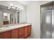 Well-lit bathroom with double sinks, vanity, large mirror, and tiled walk-in shower at 109 Pecan Pass, Ocala, FL 34472