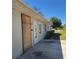 Exterior side of the home with gray painted brick and visible boarded door at 115 N Galena Ave, Minneola, FL 34715