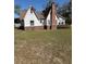 Rear view of a Tudor-style home featuring a brick chimney and expansive grassy backyard at 1326 East Ave, Clermont, FL 34711