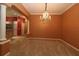 Dining room with neutral carpet, an elegant chandelier, and an open view to the modern kitchen at 17274 Se 85Th Willowick Cir, The Villages, FL 32162