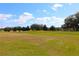 Scenic golf course with lush green fairways and mature trees against a backdrop of a bright blue sky at 17274 Se 85Th Willowick Cir, The Villages, FL 32162