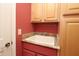 This laundry room features a white utility sink, granite counters, and upper and lower wood cabinets at 17274 Se 85Th Willowick Cir, The Villages, FL 32162