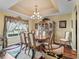 Formal dining room with a chandelier, tray ceiling, and a large window providing ample natural light at 17378 Se 110Th Ter, Summerfield, FL 34491