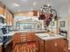 Spacious kitchen featuring wood cabinetry, an island, and a unique pot rack over the sink at 17378 Se 110Th Ter, Summerfield, FL 34491