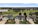 An aerial view of a well-manicured lawn and landscaping for multiple homes overlooking a golf course and pond at 1755 Lakewood Dr, The Villages, FL 32162