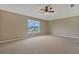 Well-lit bedroom featuring neutral walls, carpeted floors, and a large window overlooking a charming neighborhood at 1787 Sunset Ridge Dr, Mascotte, FL 34753