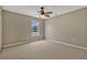 Neutral colored room with a ceiling fan, carpeted floors, and a large window for ample natural lighting at 1787 Sunset Ridge Dr, Mascotte, FL 34753