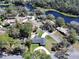 Aerial view of a charming home with a circular driveway, surrounded by mature trees and water views at 1930 Hilltop Dr, Mount Dora, FL 32757