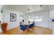 Bright dining area with a glass-top table, stylish blue chairs, modern light fixture, and view of the front yard at 1930 Hilltop Dr, Mount Dora, FL 32757