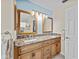 Bathroom featuring double sinks, granite counters, wooden cabinets and framed mirrors at 2175 Madero Dr, The Villages, FL 32159