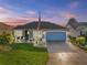 Charming home featuring a well-maintained lawn, lovely landscaping, and a blue garage door at 2175 Madero Dr, The Villages, FL 32159