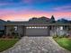 Charming home featuring a manicured lawn and paved driveway leading to an attached two-car garage at 21849 Tartan St, Leesburg, FL 34748