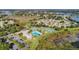 An aerial view of the community center with a pool, tennis courts, parking lot, and nearby ponds at 21850 Tartan St, Leesburg, FL 34748