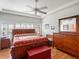 Bright bedroom with wood furniture, flooring, and a red accent chest at 21850 Tartan St, Leesburg, FL 34748