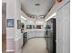Open kitchen features white cabinetry, black appliances, neutral countertops, and tile flooring at 21850 Tartan St, Leesburg, FL 34748