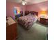 Cozy bedroom featuring light pink walls, a ceiling fan, and a queen-sized bed with floral bedding at 25124 Twelve Oaks Rd, Leesburg, FL 34748