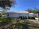 View of the side of the home showcasing light-colored siding and mature trees at 25124 Twelve Oaks Rd, Leesburg, FL 34748