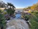 Tranquil backyard water feature with bridge, lush landscaping, and distant lake view, perfect for relaxation and enjoyment at 25124 Twelve Oaks Rd, Leesburg, FL 34748