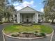 View of the clubhouse featuring a circular driveway, manicured lawn, and symmetrical columns at 25212 Clifford Hl, Leesburg, FL 34748