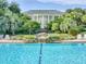 Outdoor pool with waterfall feature and view of the large clubhouse and surrounding palm trees at 25212 Clifford Hl, Leesburg, FL 34748