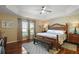 Inviting bedroom with tray ceiling, natural light, a decorative accent wall, and wood-look flooring at 2882 Adrienne Way, The Villages, FL 32163