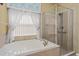 Bright bathroom featuring a large soaking tub and glass-enclosed shower at 303 White Water Bay Dr, Groveland, FL 34736