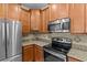 Modern kitchen featuring stainless steel appliances, granite countertops, and wooden cabinetry at 3206 Sonesta Ct # A, Clermont, FL 34711