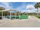 Outdoor bocce ball court with green turf, benches, and shaded seating area with landscaping and clear sky at 32222 Summertree Circle, Leesburg, FL 34748