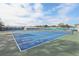 A blue and green outdoor tennis court enclosed by fencing and landscaping with some buildings in the background at 32222 Summertree Circle, Leesburg, FL 34748