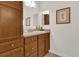 Bathroom boasts wood cabinets, neutral countertops, and decorative art on the walls at 3262 Dalkeith Ter, The Villages, FL 32163