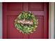 A charming welcome wreath with a wooden 'welcome' sign adorns the burgundy front door at 330 N Sunset Dr, Mount Dora, FL 32757