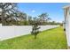 Large grassy back yard featuring a white vinyl fence and treeline at 3320 Davis Ter, The Villages, FL 32163