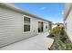 Side view of the home showing the light gray siding, sliding glass doors, and manicured landscaping at 3320 Davis Ter, The Villages, FL 32163