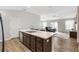 Open kitchen featuring an island with stainless steel dishwasher and faucet with dark brown cabinetry and adjacent living room at 3320 Davis Ter, The Villages, FL 32163