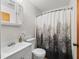 A functional bathroom with a sink, toilet, and shower featuring a decorative curtain at 422 W Hunt Ave, Bushnell, FL 33513