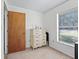 A simple bedroom featuring a dresser, soft carpeting, and a window that provides natural light at 422 W Hunt Ave, Bushnell, FL 33513