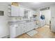 Bright kitchen features white cabinets, tile flooring, and appliances, with a laundry area visible in the background at 422 W Hunt Ave, Bushnell, FL 33513