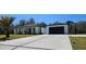 Long concrete driveway leading to a modern house and detached garage with dark trim accents at 42329 Chinaberry St, Eustis, FL 32736