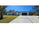 Inviting home exterior with lush green lawn, long driveway, and two-car detached garage at 42329 Chinaberry St, Eustis, FL 32736