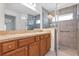 Bathroom featuring a glass shower, wood cabinets, granite countertops and a large mirror at 4331 Arlington Ridge Blvd, Leesburg, FL 34748